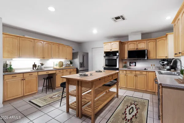 a open kitchen with stainless steel appliances granite countertop a stove top oven a sink dishwasher a dining table and chairs with wooden floor