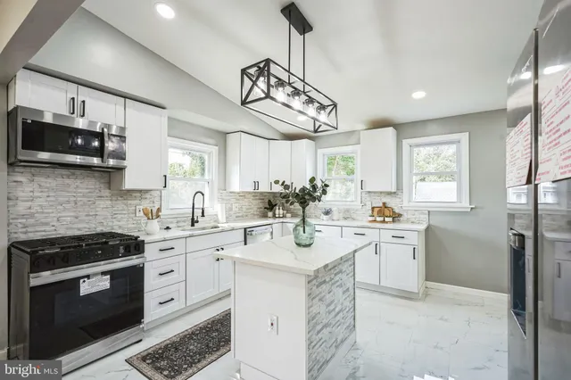 a kitchen with stainless steel appliances a white stove top oven a sink dishwasher and a refrigerator with wooden floor