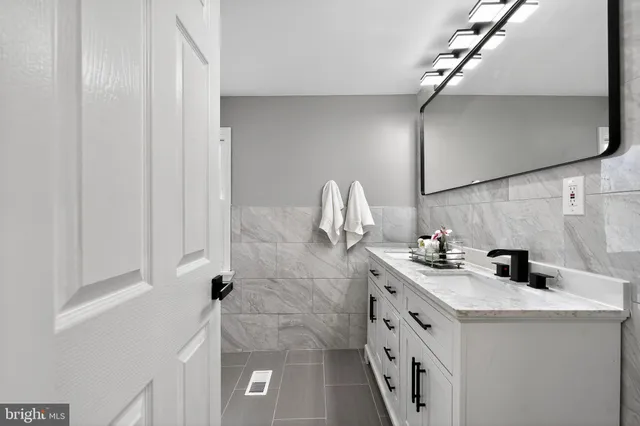 a bathroom with a sink and mirror with bathtub