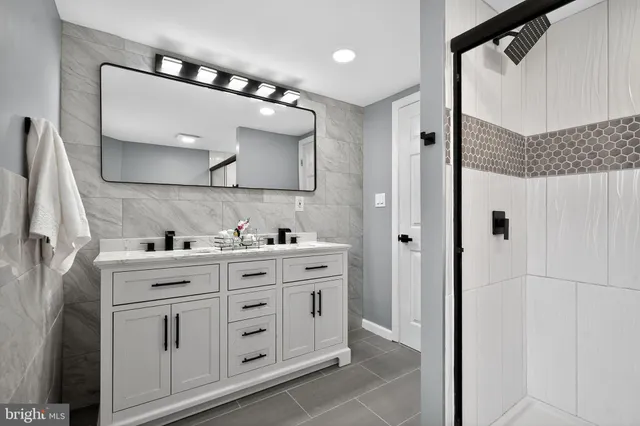 a spacious bathroom with a double vanity sink a mirror and a shower