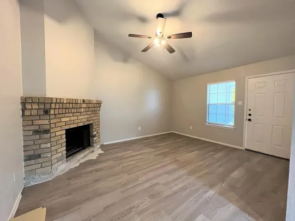 an empty room with wooden floor fan and windows