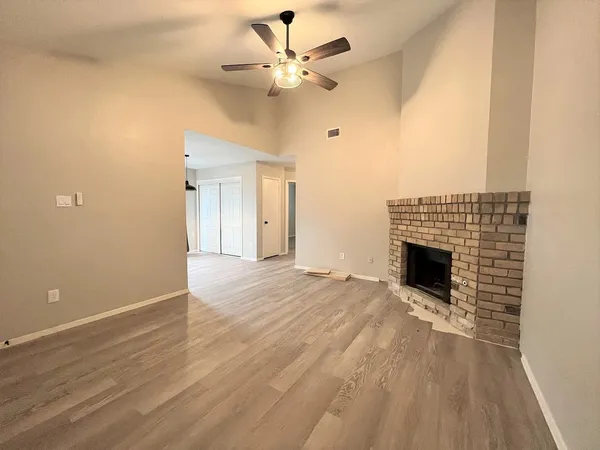 an empty room with fan and a fireplace
