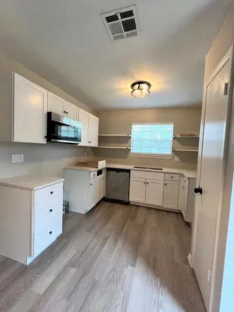 a kitchen with stainless steel appliances a sink cabinets and wooden floor