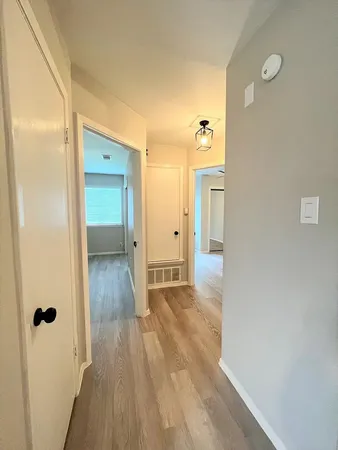 a view of a hallway with wooden floor and a bathroom