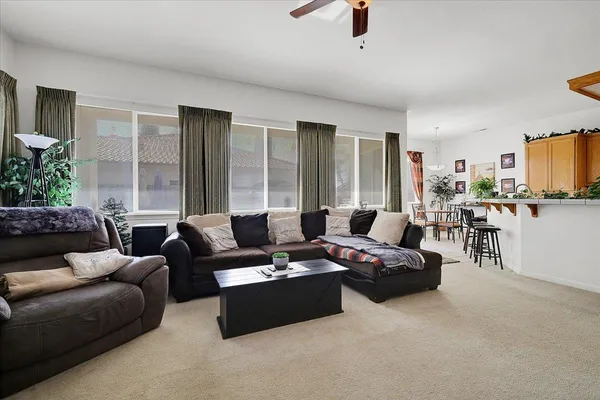 a living room with furniture a rug and a dining table with wooden floor