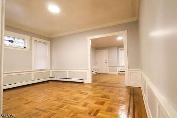 a view of an empty room with window and wooden floor