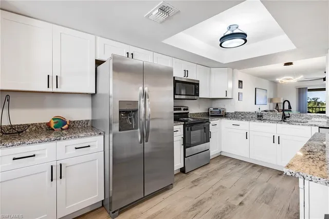 a kitchen with white cabinets and stainless steel appliances