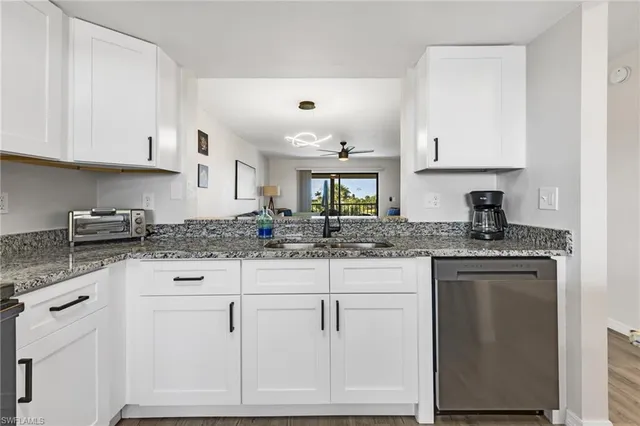 a kitchen with granite countertop white cabinets and white appliances