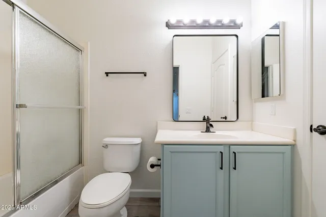 a bathroom with a toilet sink vanity and mirror