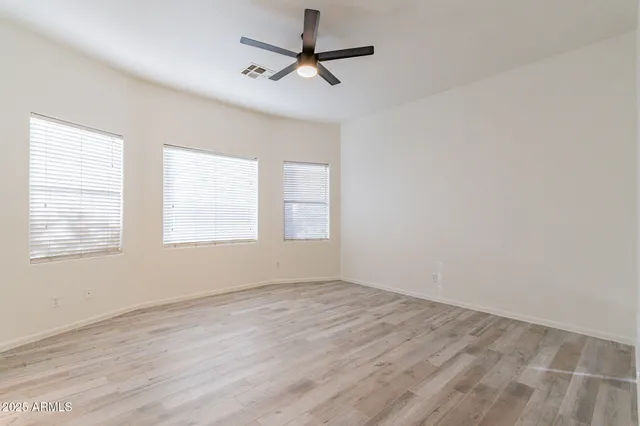 a view of empty room with wooden floor and fan