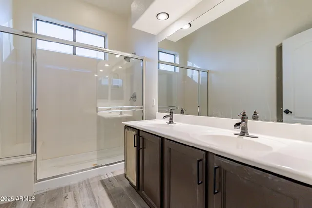 a bathroom with a double vanity sink mirror and shower