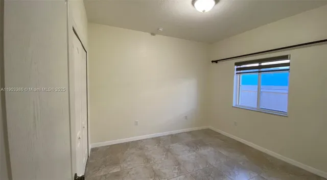 a view of an empty room with closet and a window