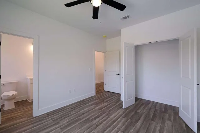 an empty room with wooden floor and a ceiling fan