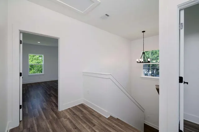 a view of a hallway with wooden floor and a bathroom