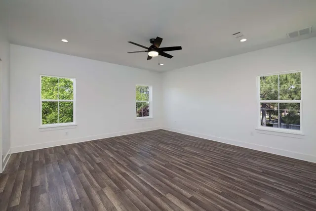 an empty room with windows and a ceiling fan
