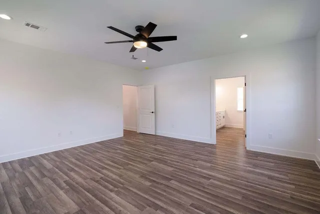a view of empty room with wooden floor and ceiling fan
