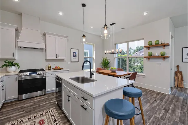 a kitchen with a stove a sink a counter space and wooden floor