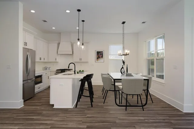 a kitchen with stainless steel appliances granite countertop a sink a stove a refrigerator and island with wooden floor