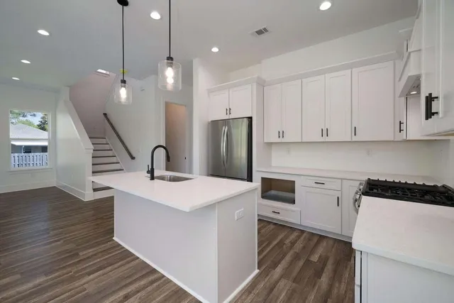 a kitchen with a sink stainless steel appliances and wooden floor