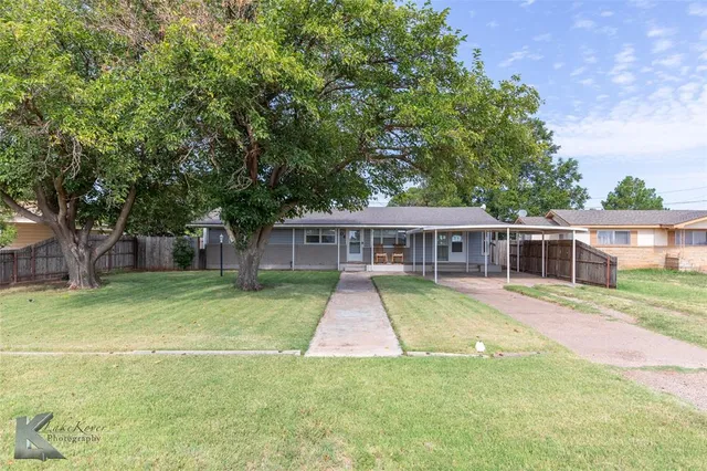 a view of house with a big yard and large trees