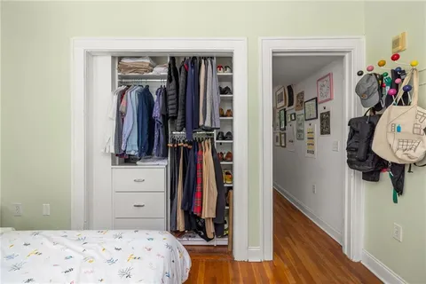 a walk in closet with wooden floor