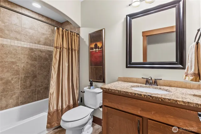a bathroom with a granite countertop sink toilet a mirror and bathtub