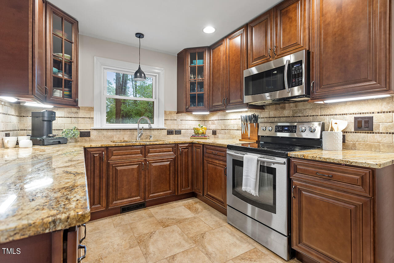 4918 Quail Hollow Drive Raleigh, NC 27609 - Photo 12 of 36 a kitchen with stainless steel appliances granite countertop wooden cabinets a stove top oven a sink and dishwasher