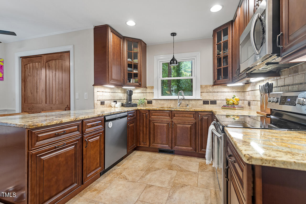 4918 Quail Hollow Drive Raleigh, NC 27609 - Photo 14 of 36 a kitchen with stainless steel appliances granite countertop a sink counter space cabinets and a large window