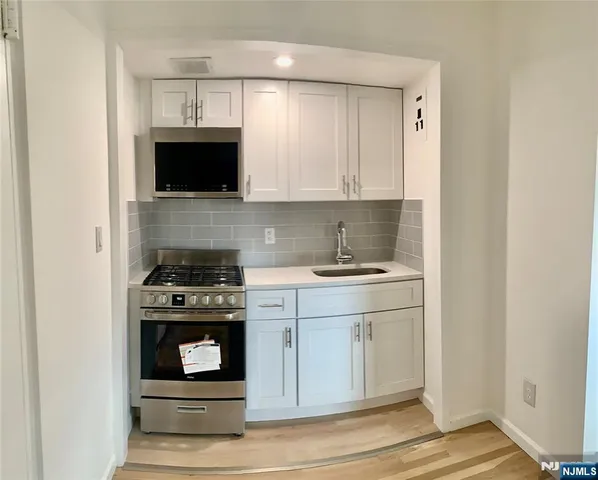 a kitchen with stainless steel appliances granite countertop white cabinets a stove top oven and sink