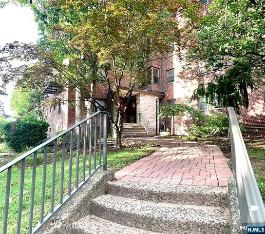 a view of a house with a small yard and large trees