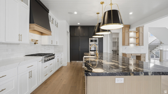 1682 North 1950 W Street, Unit 9 Provo, UT 84604 - Photo 20 of 84 Kitchen featuring a large island with a patterned countertop, white perimeter cabinetry, a stainless steel range with a pot filler faucet, and wood-finish flooring