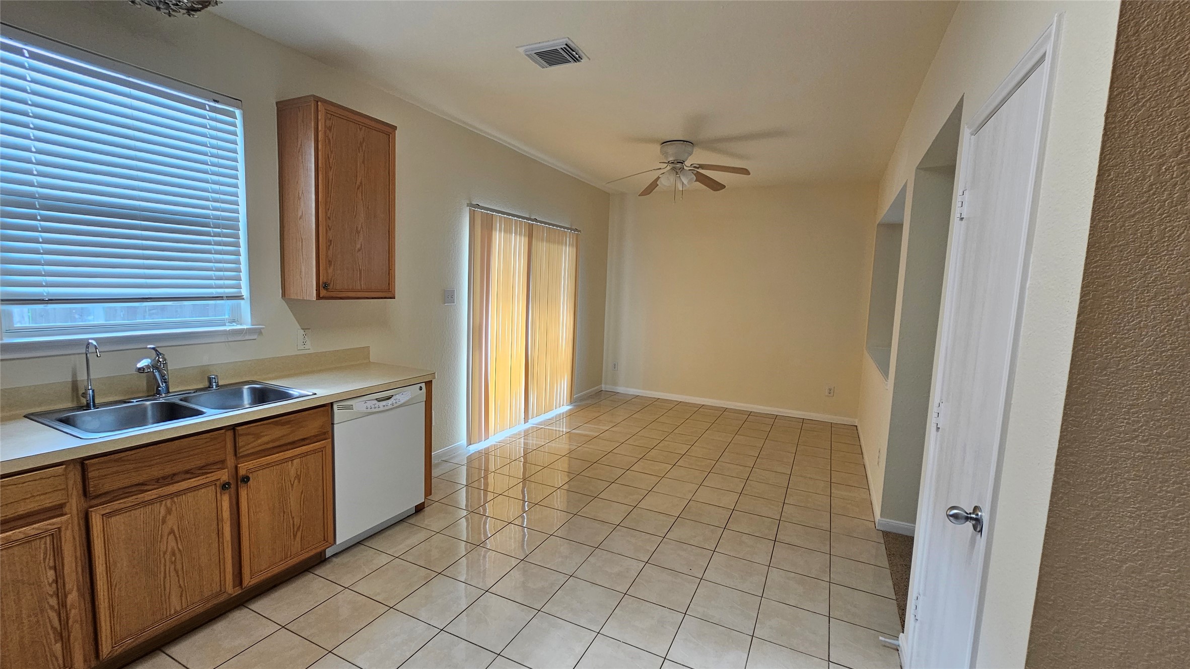 7918 Barnes Ridge Lane Houston, TX 77072 - Photo 8 of 34 Bright, open kitchen and dining area with tiled floors, wooden cabinets, and ample natural light. Features include a double sink, dishwasher, and ceiling fan, with sliding doors leading to an outdoor space.
