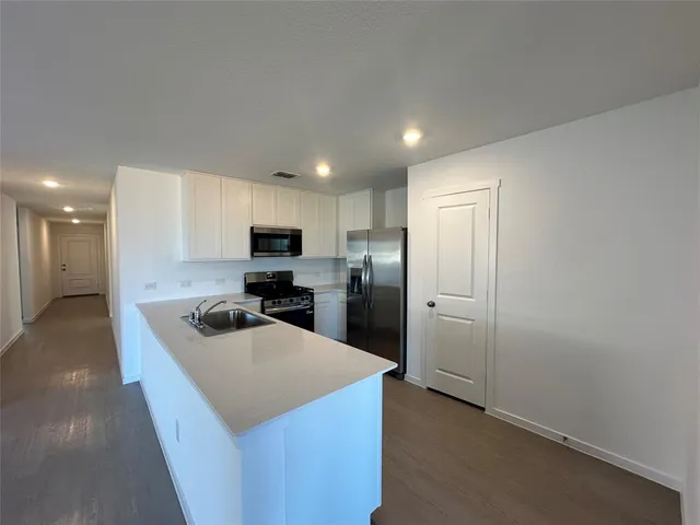 a kitchen with a refrigerator a sink and a stove top oven with wooden floor