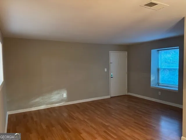 an empty room with wooden floor and windows