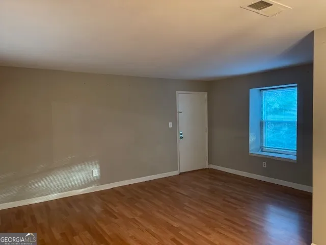 an empty room with wooden floor and bathroom view