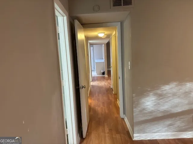 a view of an empty room with window and wooden floor