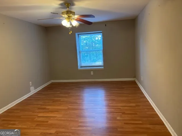 an empty room with wooden floor fan and window