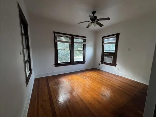 a view of an empty room with a window and wooden floor