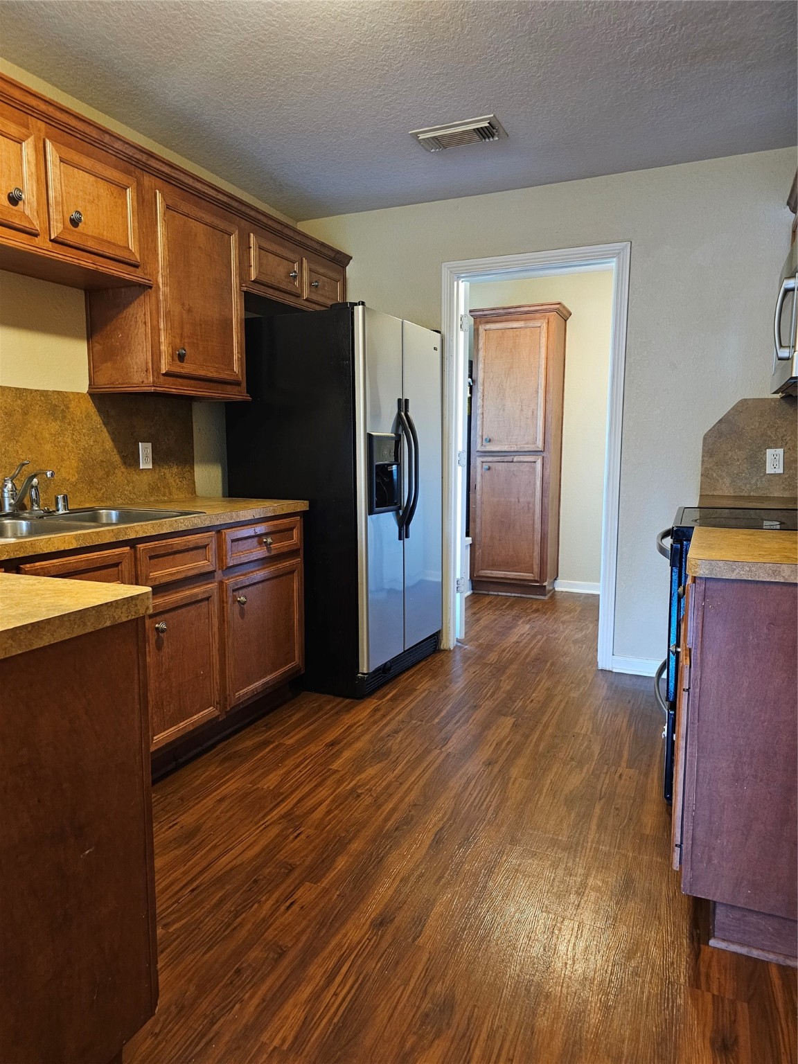 4426 25th Street East, Unit C Dickinson, TX 77539 - Photo 14 of 31 a kitchen with stainless steel appliances granite countertop a refrigerator a sink dishwasher and wooden cabinets with wooden floor