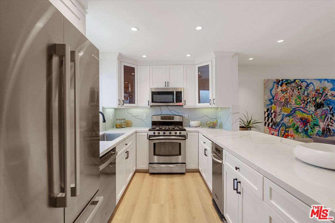 2108 Neilson Way Santa Monica, CA 90405 - Photo 11 of 70 a kitchen with white cabinets and stainless steel appliances