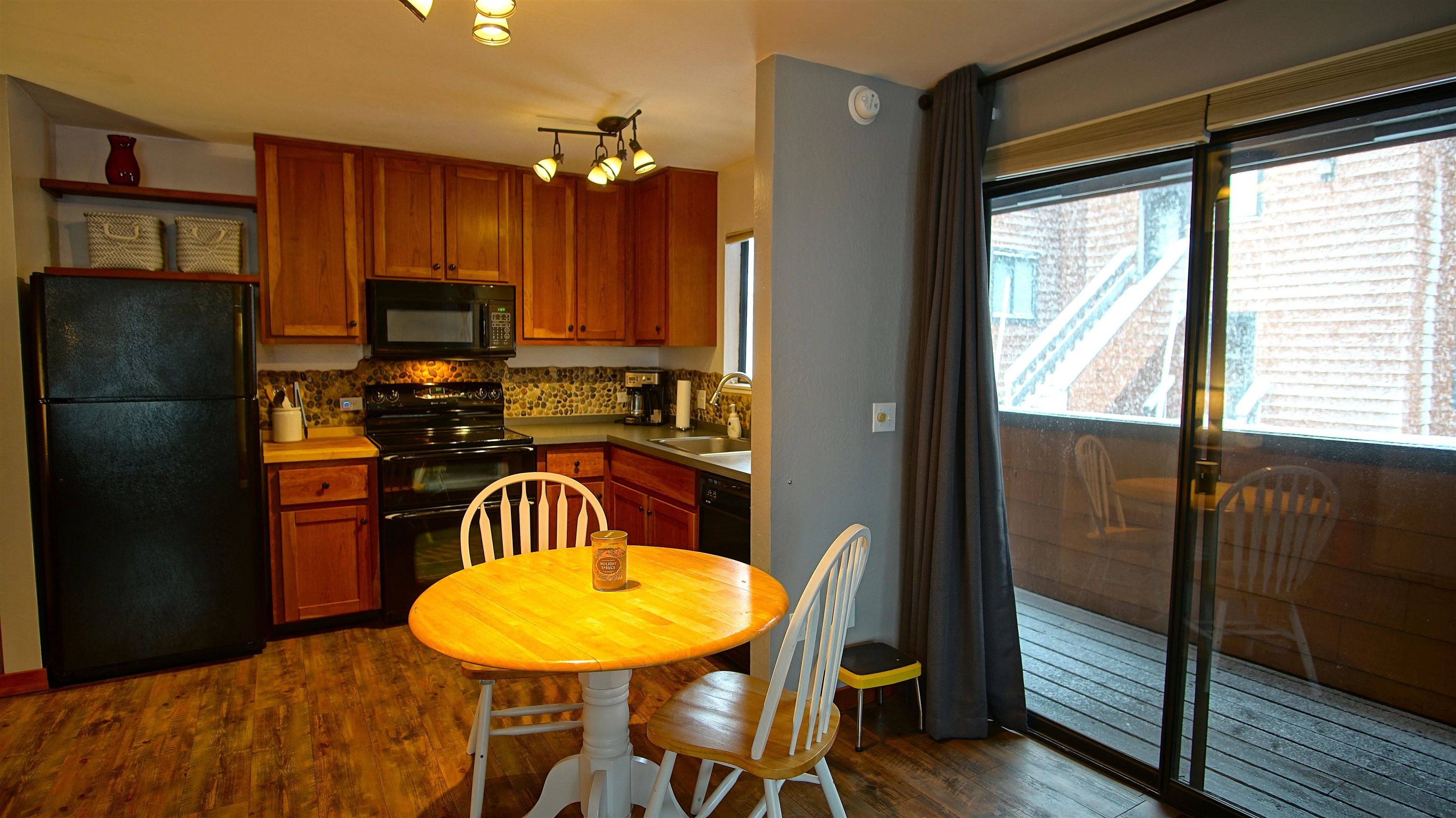 11723 Snowpeak Way, Unit 567 Truckee, CA 96161 - Photo 5 of 28 a kitchen with stainless steel appliances granite countertop a refrigerator a stove a sink dishwasher with a dining table and chair with wooden floor