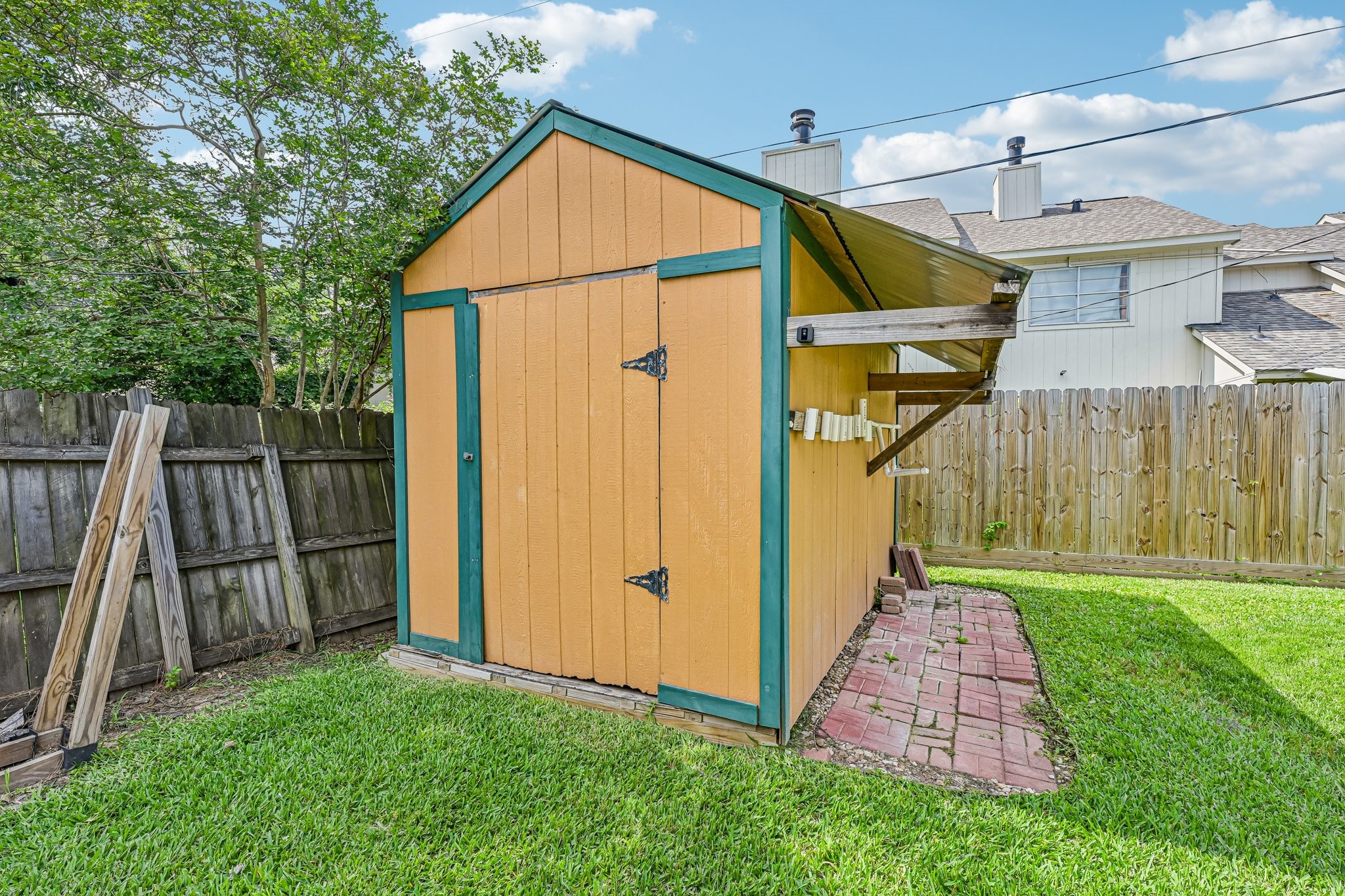 8 Arlington Street Conroe, TX 77301 - Photo 34 of 37 This photo shows a small backyard shed. It's situated on a grassy area with a mix of wooden and brick pathways.