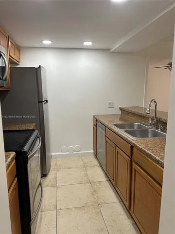 a kitchen with a sink a refrigerator and cabinets