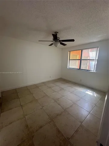 an empty room with windows and ceiling fan