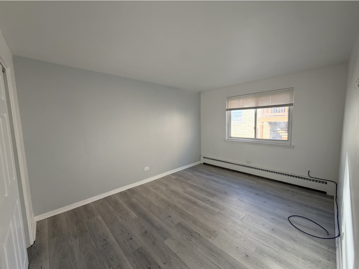 2033 West 111th Street, Unit 2S Chicago, IL 60643 - Photo 4 of 8 an empty room with wooden floor and windows