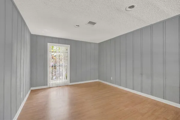 an empty room with wooden floor fireplace and windows
