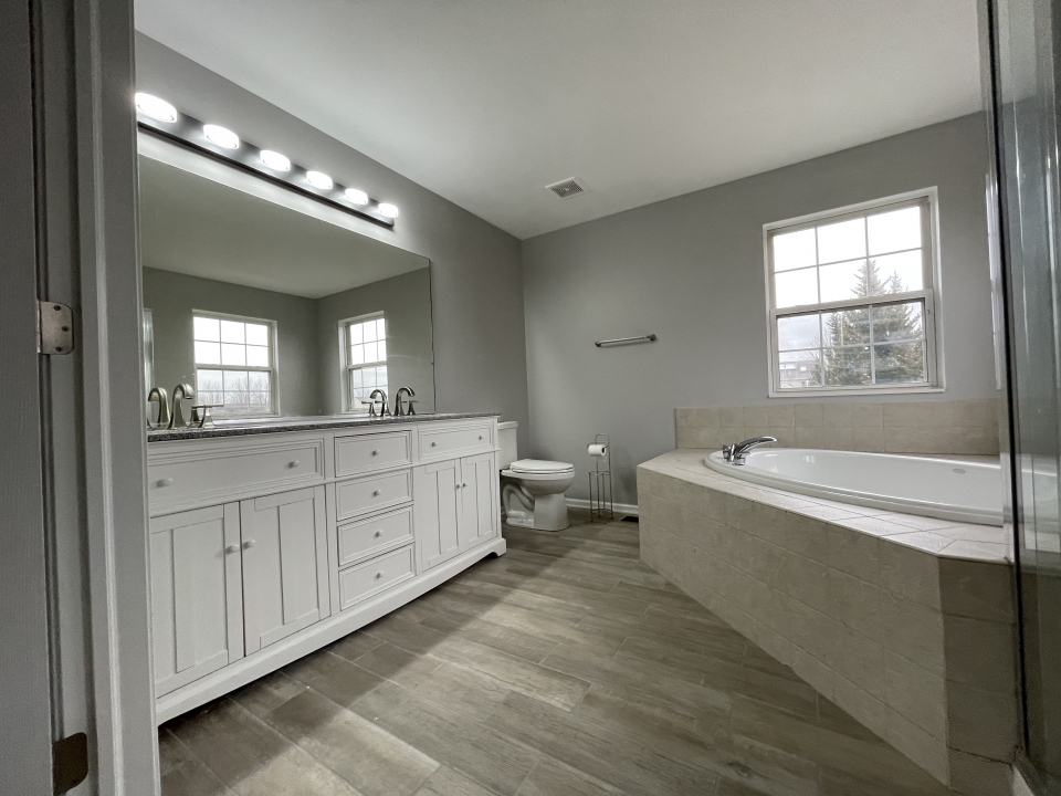 1303 Bridgehampton Drive Plainfield, IL 60586 - Photo 13 of 29 a spacious bathroom with a granite countertop tub a double vanity sink a mirror and a window