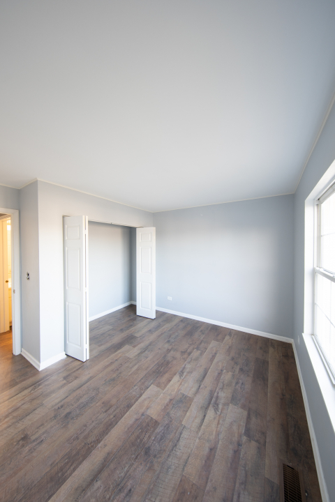 1303 Bridgehampton Drive Plainfield, IL 60586 - Photo 18 of 29 an empty room with wooden floor and windows