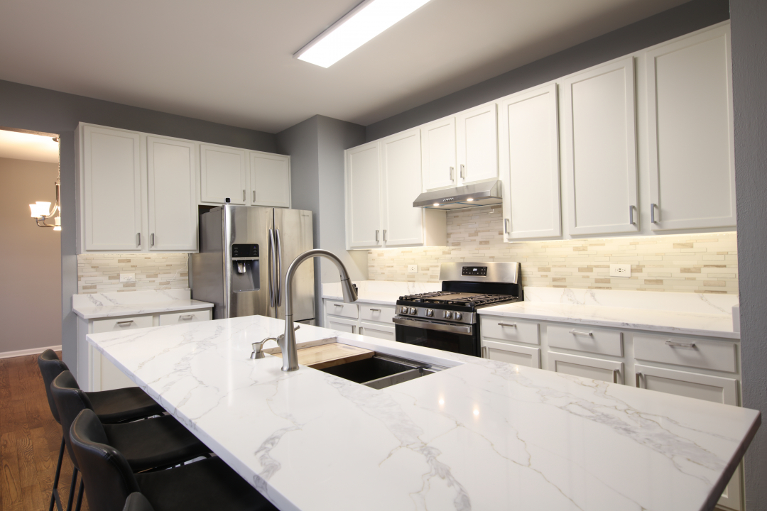 1303 Bridgehampton Drive Plainfield, IL 60586 - Photo 5 of 29 a kitchen with kitchen island a sink a stove and white cabinets