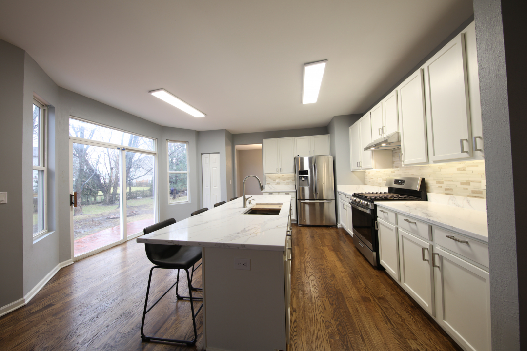 1303 Bridgehampton Drive Plainfield, IL 60586 - Photo 6 of 29 a kitchen with stainless steel appliances kitchen island granite countertop a stove a sink and white cabinets with wooden floors